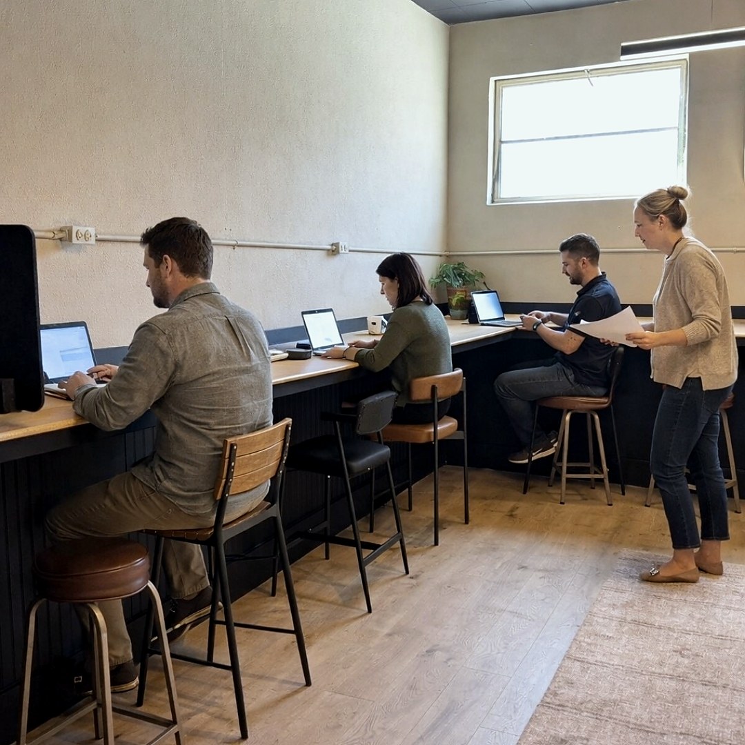 Four members working side by side at the shared counter in the open lounge at 635 Main Street